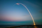 An arced trail from a rocket ship as it launches into space at dawn